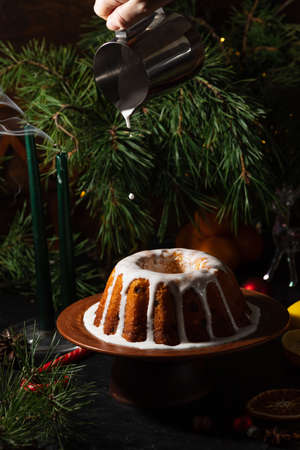 a round cupcake on a dark background is poured from a saucepan with icing on topの写真素材