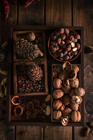 a wooden tray full of different types of nuts. whole and chopped nuts in different boxes nextの写真素材