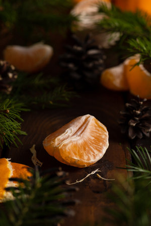 tangerine slices lie on a wooden table surrounded by green spruce twigsの写真素材