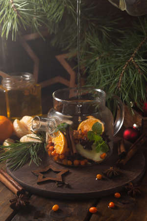 boiling water is poured into a transparent kettle with sliced fruits and spicesの写真素材