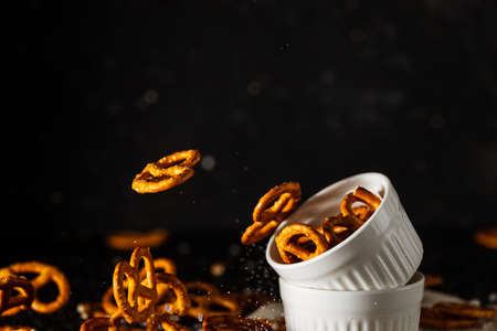 pretzels with salt fall from a white cup.の写真素材