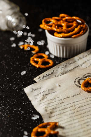 the recipe for making pretzels is written on a piece of paper, next to it lies salt and pretzels.の写真素材