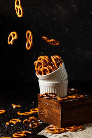 pretzels with salt fall from a white cup.の写真素材