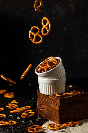 pretzels with salt fall from a white cup.の写真素材