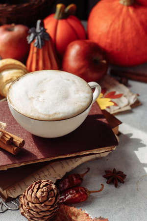 autumn layout. a mug of coffee, apples and spices are lying near the bookの写真素材