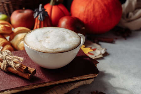 autumn layout. a mug of coffee, apples and spices are lying near the bookの写真素材