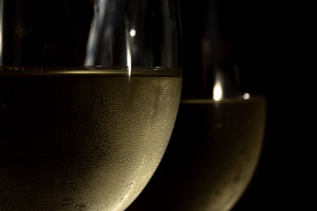 macro photo of two glasses of white wine. glasses with chilled wine in it and condensationの写真素材