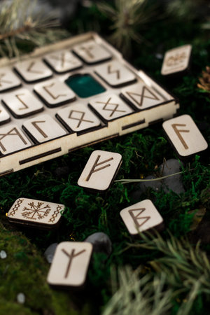 set of wooden runes in a box lie on the moss in the forest. rectangular wooden platforms on which...