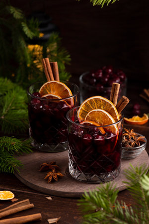 Two glasses on a wooden tray with mulled wine. Berries, orange slices and cinnamon sticks decorate the glassesの写真素材