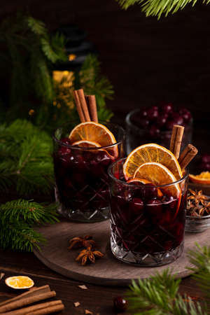 Two glasses on a wooden tray with mulled wine. Berries, orange slices and cinnamon sticks decorate the glassesの写真素材