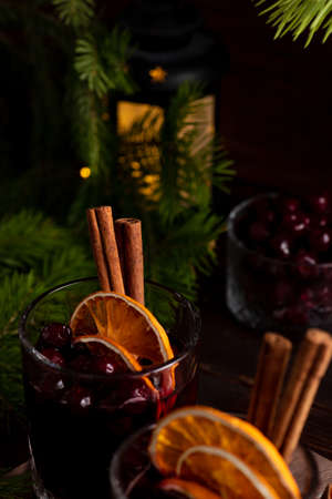 Two glasses on a wooden tray with mulled wine. Berries, orange slices and cinnamon sticks decorate the glassesの写真素材