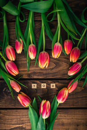 Pink tulips are lying on a wooden table in the shape of a heart.の写真素材