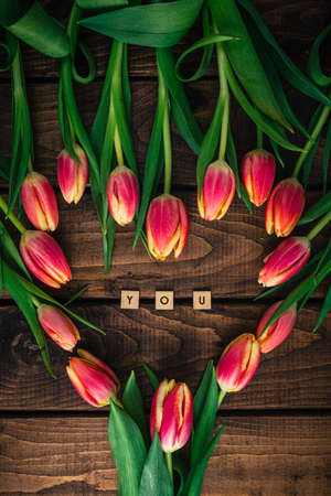 Pink tulips are lying on a wooden table in the shape of a heart.の写真素材