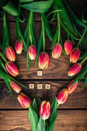 Pink tulips are lying on a wooden table in the shape of a heart.の写真素材