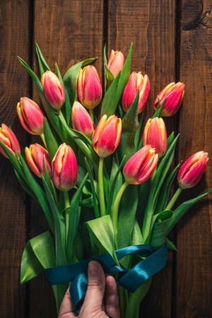 A bouquet of tulips lies on a brown wooden backgroundの写真素材