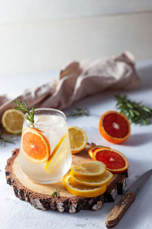 A glass and a decanter of lemonade. Lemon and grapefruit slices with rosemary leaves in a drinkの写真素材