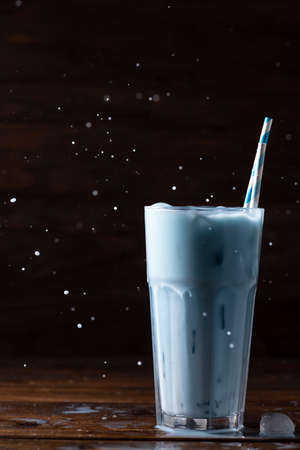 Blue latte in a tall glass glass with two straws. The spray is flying up.の写真素材