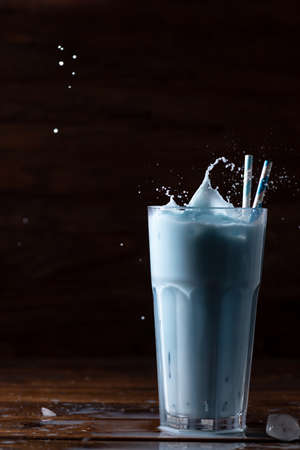 Blue latte in a tall glass glass with two straws. The spray is flying up.の写真素材