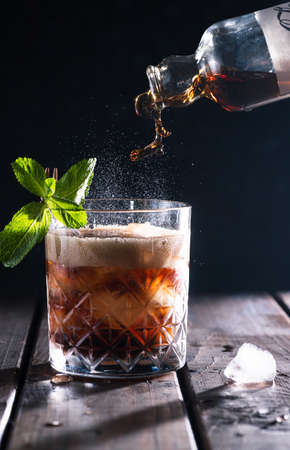 Cola is poured into a glass with ice.の写真素材