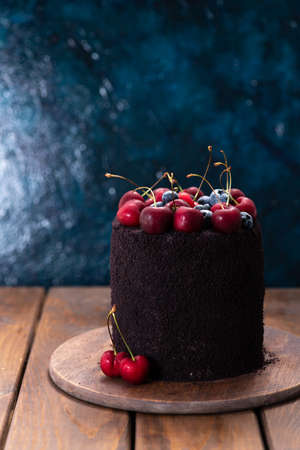 Dark cake with berries on top. A cake decorated with blueberries and cherries.の写真素材