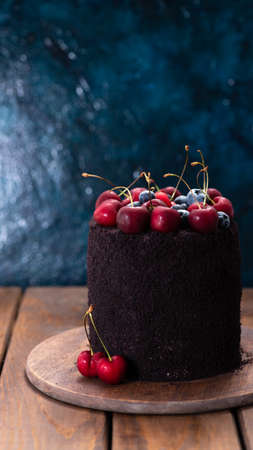 Dark cake with berries on top. A cake decorated with blueberries and cherries.の写真素材
