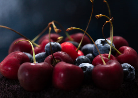 Dark cake with berries on top. A cake decorated with blueberries and cherries.の写真素材