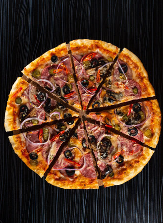 bright pizza on a dark table. pizza with olives and red pepperの写真素材