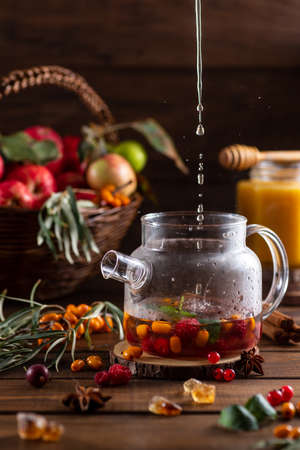 Boiling water is poured into a kettle with berries and spicesの写真素材