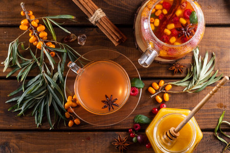 Autumn tea with berries and honey. Sea buckthorn and raspberries in a glass teapot, cups with poured...