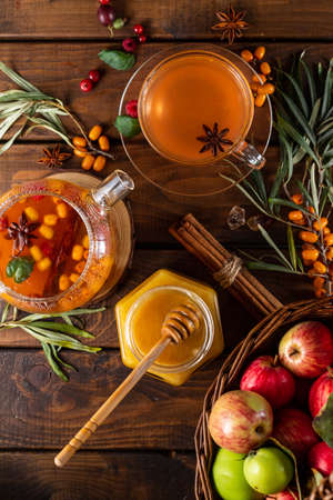Autumn tea with berries and honey. Sea buckthorn and raspberries in a glass teapot, cups with poured teaの写真素材
