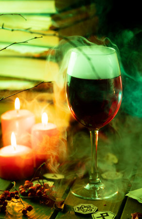 A glass of steaming wine on the table next to books and candlesの写真素材