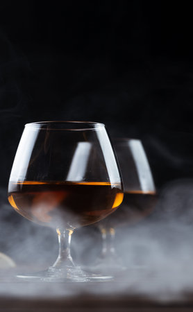 Two glasses of cognac are on a wooden table