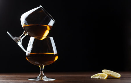 Two glasses of cognac are on a wooden table