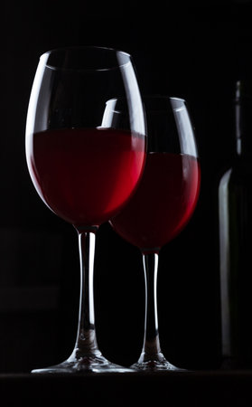 Glasses with red wine and bottle silhouetteの写真素材