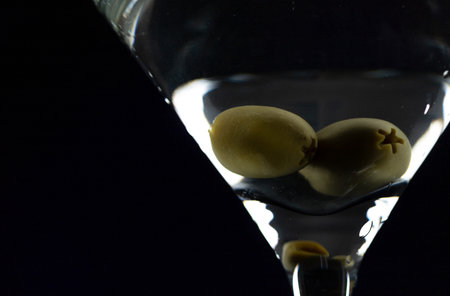A martini in a triangular glass with olives is on the tableの写真素材