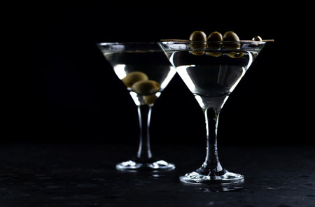 A martini in a triangular glass with olives is on the tableの写真素材