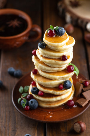 Pancakes with berries are stacked. Pancakes poured with honeyの写真素材
