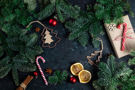 On the table is a gift surrounded by Christmas tree branches, wooden toys and spicesの写真素材