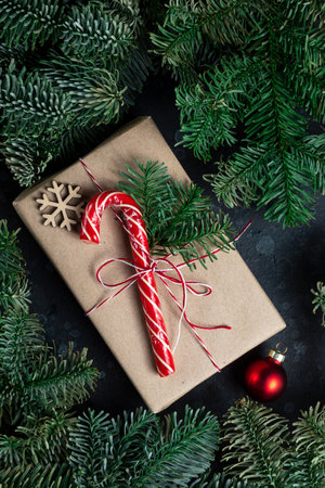 On the table is a gift surrounded by Christmas tree branches, wooden toys and spicesの写真素材