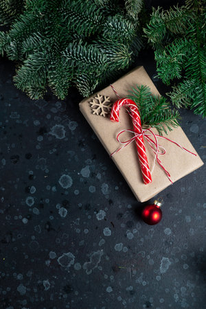 On the table is a gift surrounded by Christmas tree branches, wooden toys and spicesの写真素材