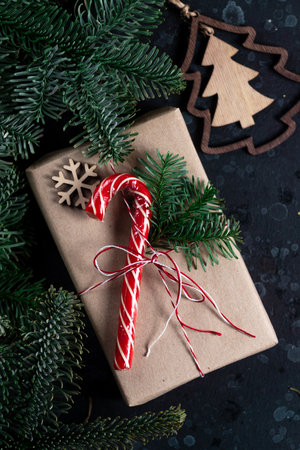 On the table is a gift surrounded by Christmas tree branches, wooden toys and spicesの写真素材