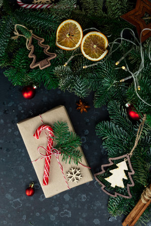 On the table is a gift surrounded by Christmas tree branches, wooden toys and spicesの写真素材