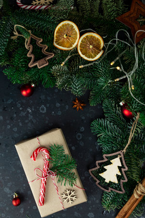 On the table is a gift surrounded by Christmas tree branches, wooden toys and spicesの写真素材