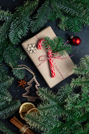 On the table is a gift surrounded by Christmas tree branches, wooden toys and spicesの写真素材