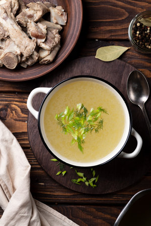 Chicken broth with dill and parsley in a bowl on wooden backgroundの写真素材