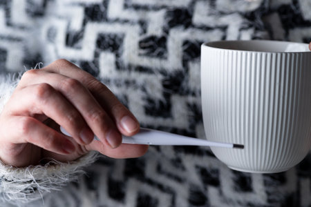 Thermometer and mug in handの写真素材