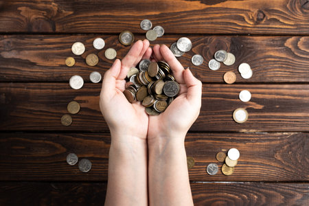 Counting coins on a wooden tableの写真素材