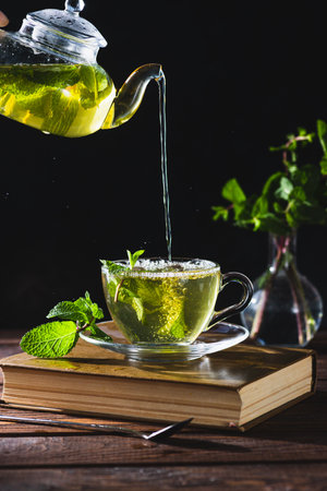 Mint tea in a teapot and cup on a wooden tableの写真素材