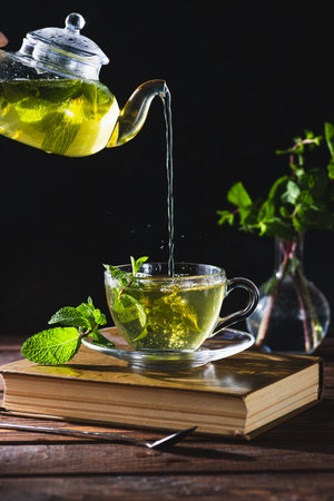 Mint tea in a teapot and cup on a wooden tableの写真素材