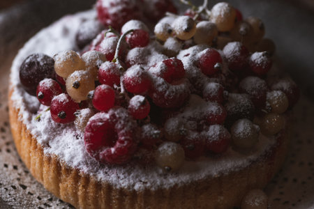 The cake with berries is sprinkled with powdered sugarの写真素材
